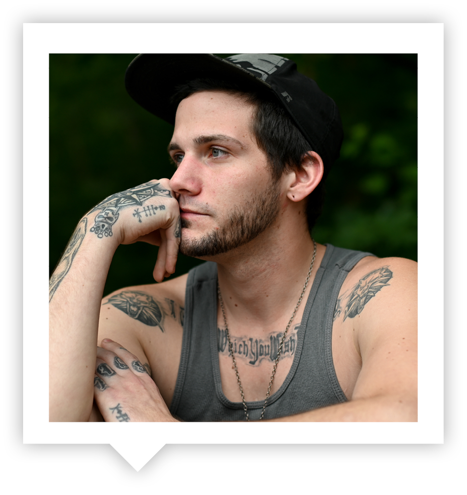 A young man with tattoos looks in the distance